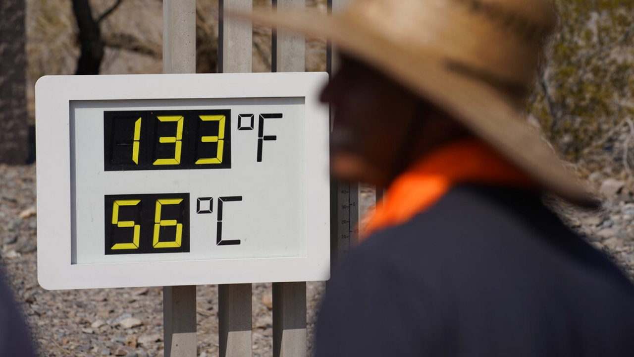 People visit a thermometer Sunday, July 11, 2021, in Death Valley National Park.