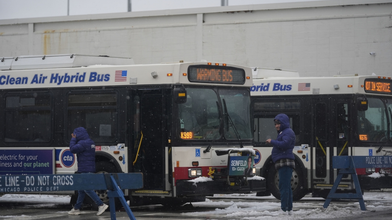 Snow falls as migrants continue to be housed by the city in "warming" buses in Chicago.
