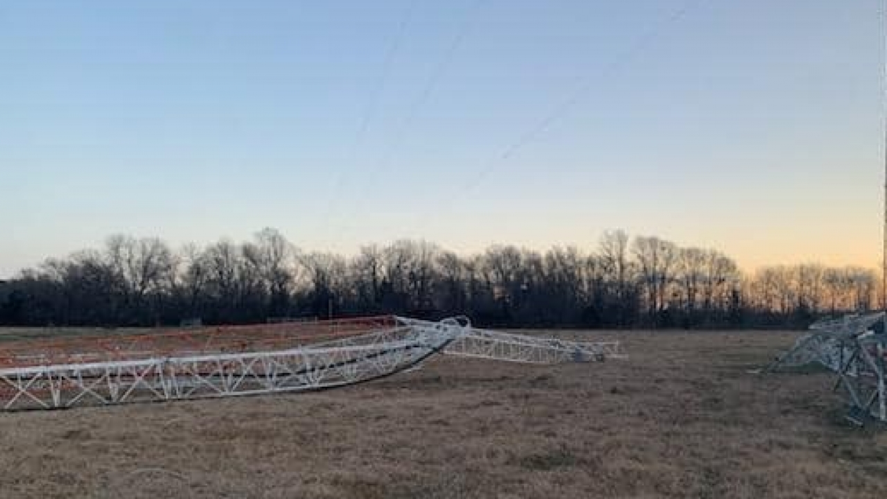 Radio tower mangled, lying on a field.