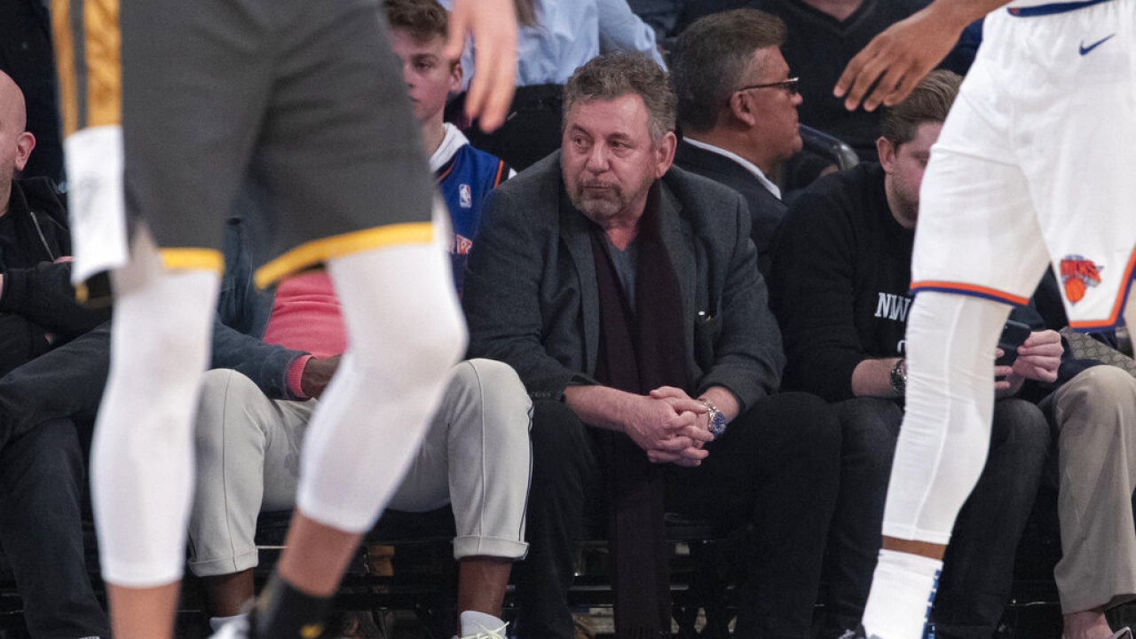 New York Knicks owner James Dolan, center, watches the first half of an NBA basketball game.
