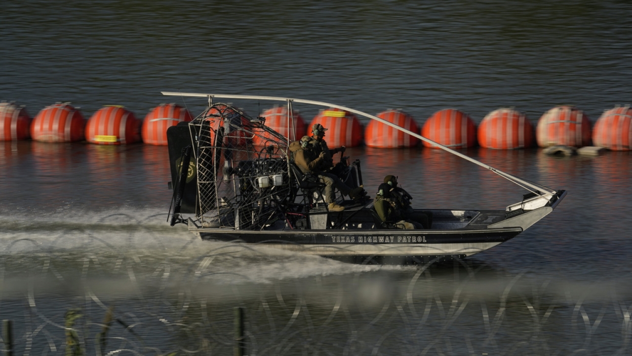 A Texas Highway Patrol boat passes a chain of buoys deployed to help curb illegal crossings along the Rio Grande.