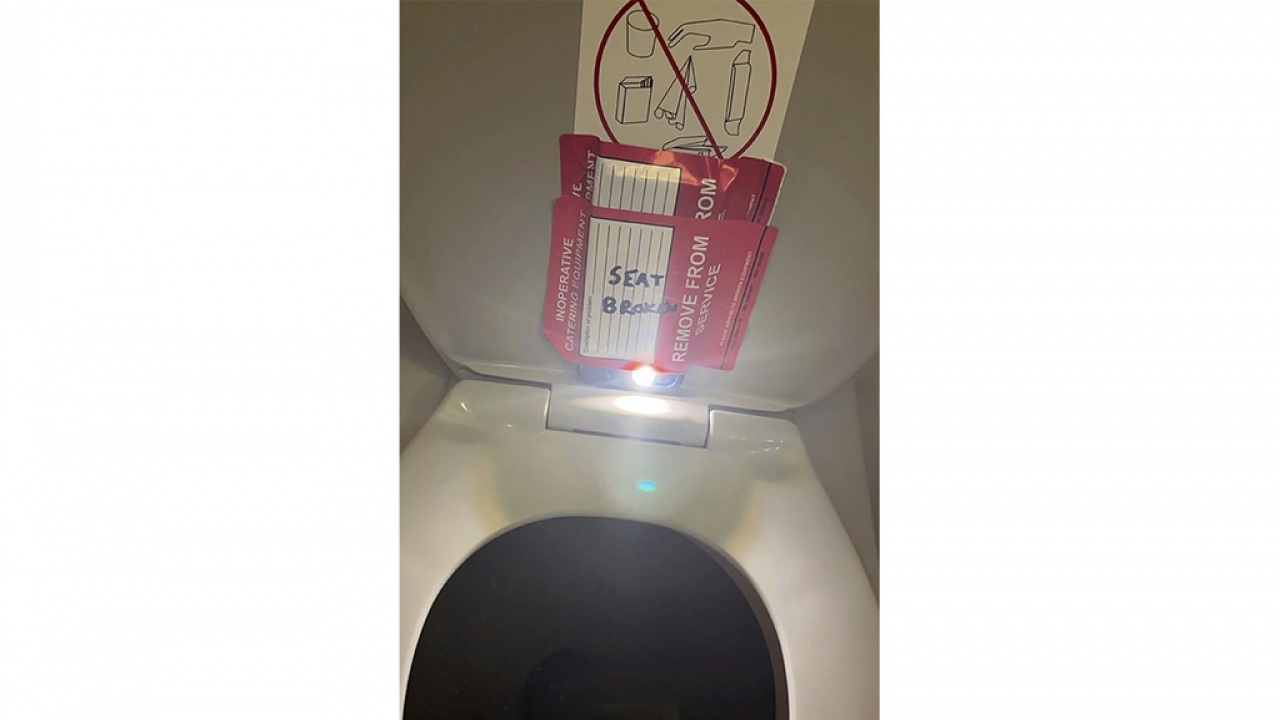 Toilet seat lid with a phone concealed behind stickers with handwriting on them