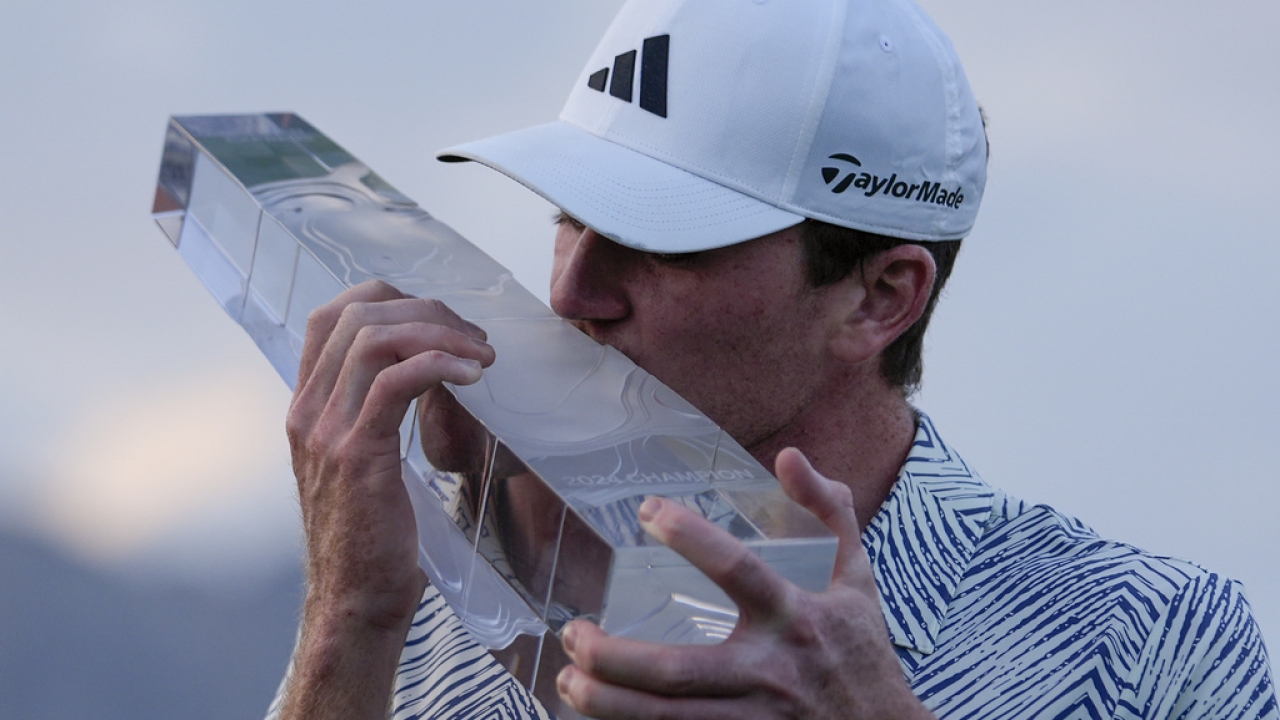 Amateur golfer Nick Dunlap kisses his trophy.