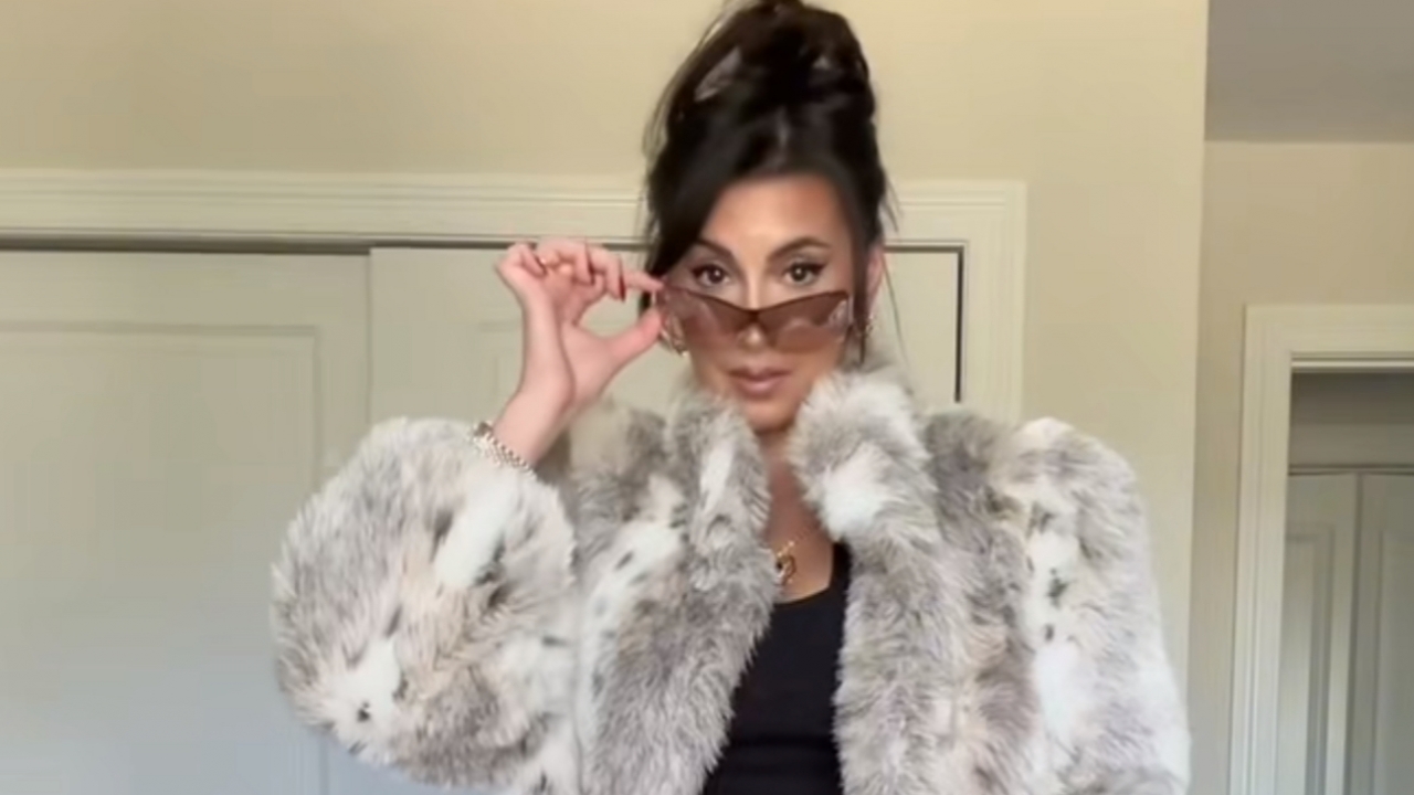 Influencer Sarah Arcuri in a faux fur, hair bun and sunglasses