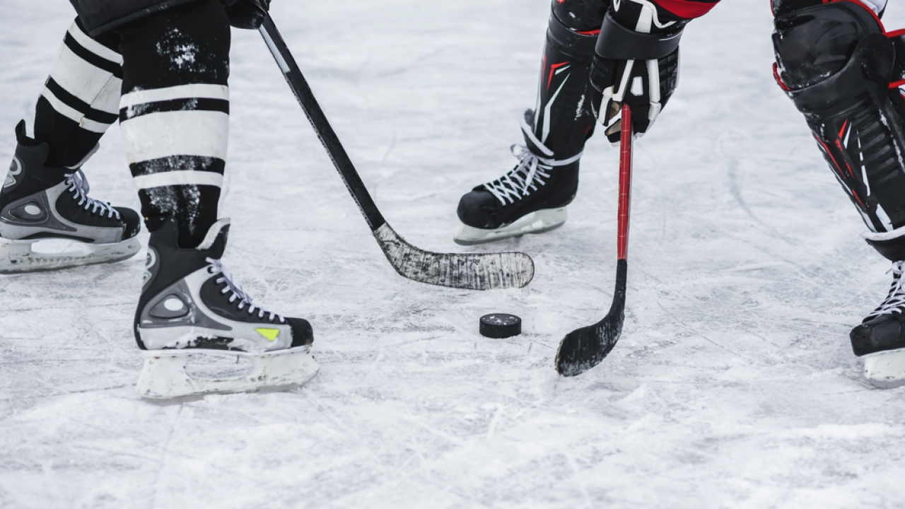 Close-up of hockey puck and two players