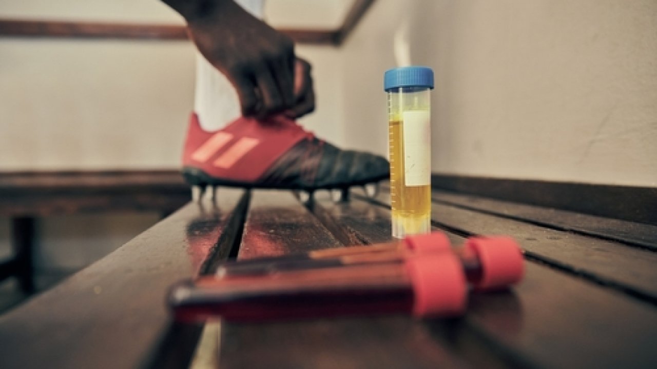 Stock image of blood and urine samples next to an athlete lacing up cleats.
