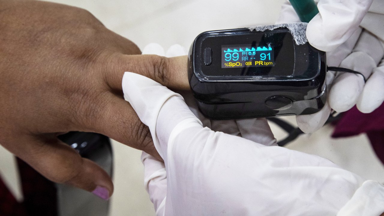 health worker uses a pulse oximeter to check the oxygen saturation level , Jan. 21, 2021