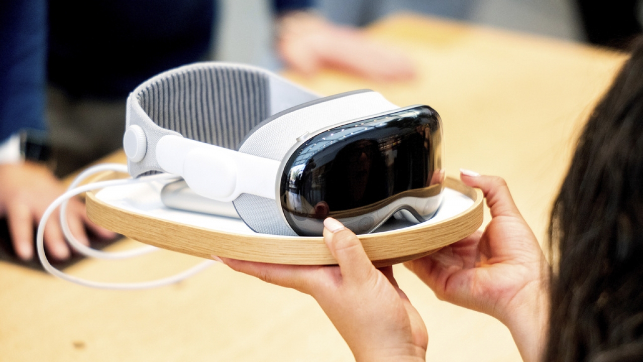 An Apple employee holds up a Vision Pro headset.