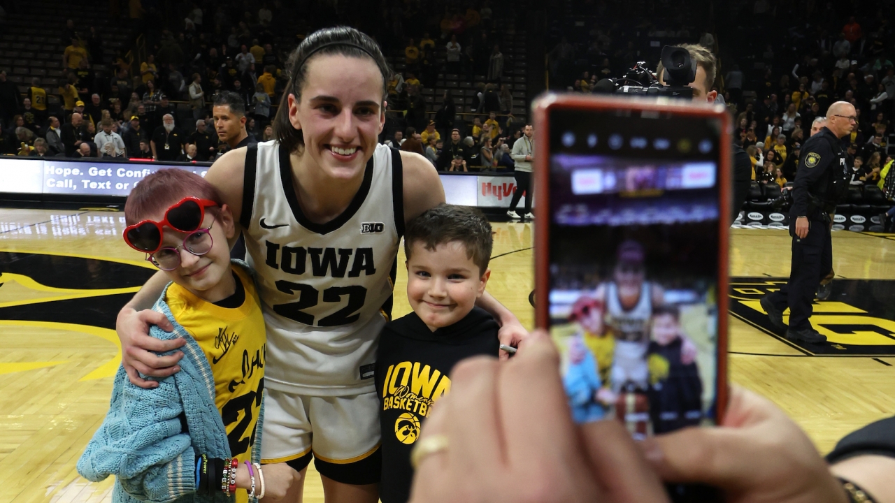 Iowa women's basketball star Caitlin Clark poses for a picture with young fans.