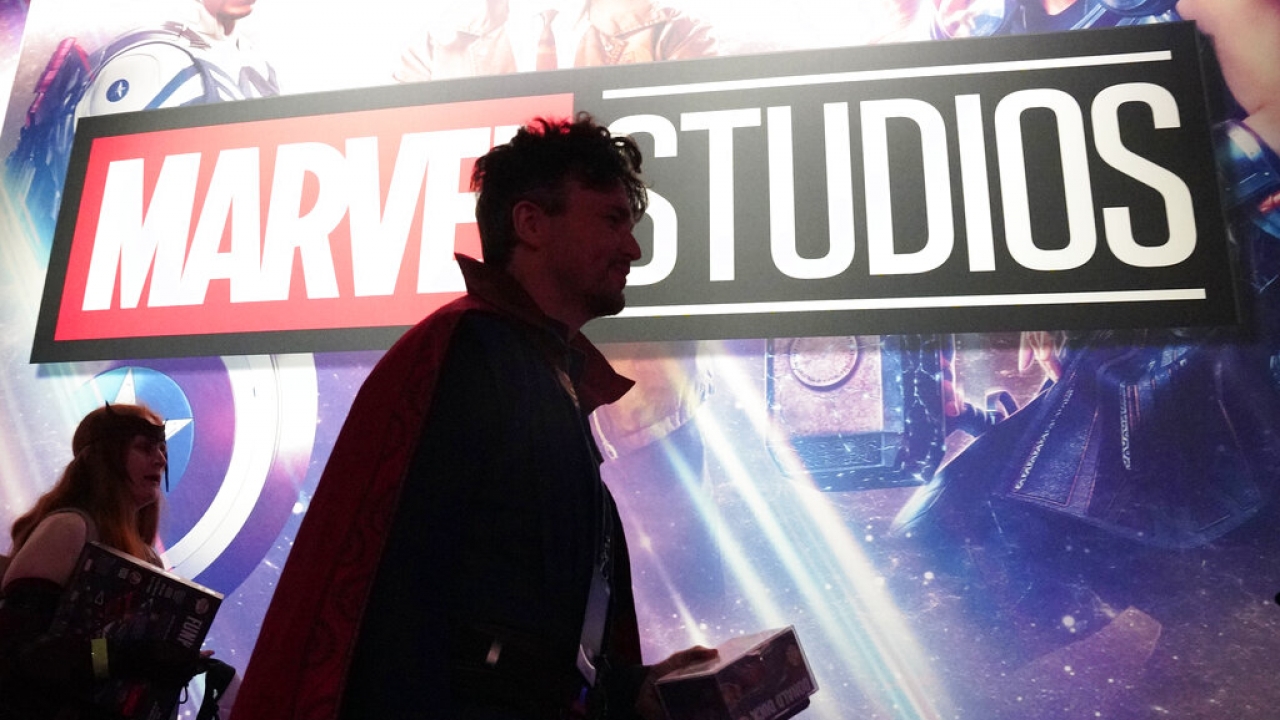 A cosplayer dressed as Doctor Strange passes by a Marvel Studios exhibit.