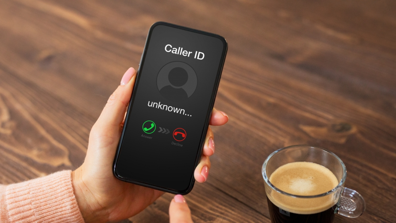 A person holds a cellphone with an unknown Caller ID.