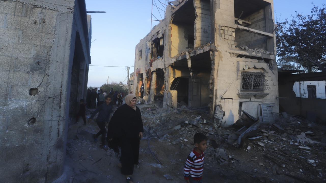 Palestinians walk by a residential building destroyed in an Israeli strike in Rafah, Gaza Strip.
