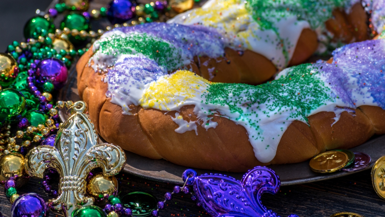 King cake surrounded by Mardi Gras decorations.