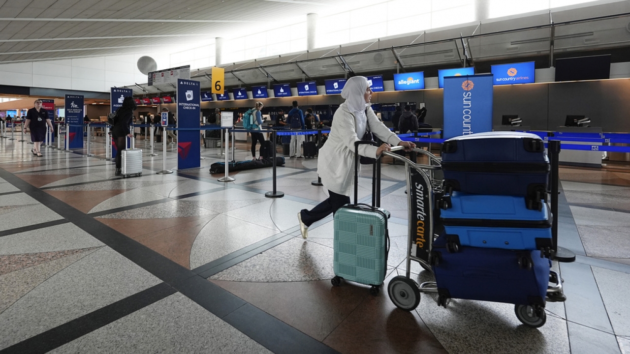 A traveler pushes a cart topped with baggage in Denver International Airport.